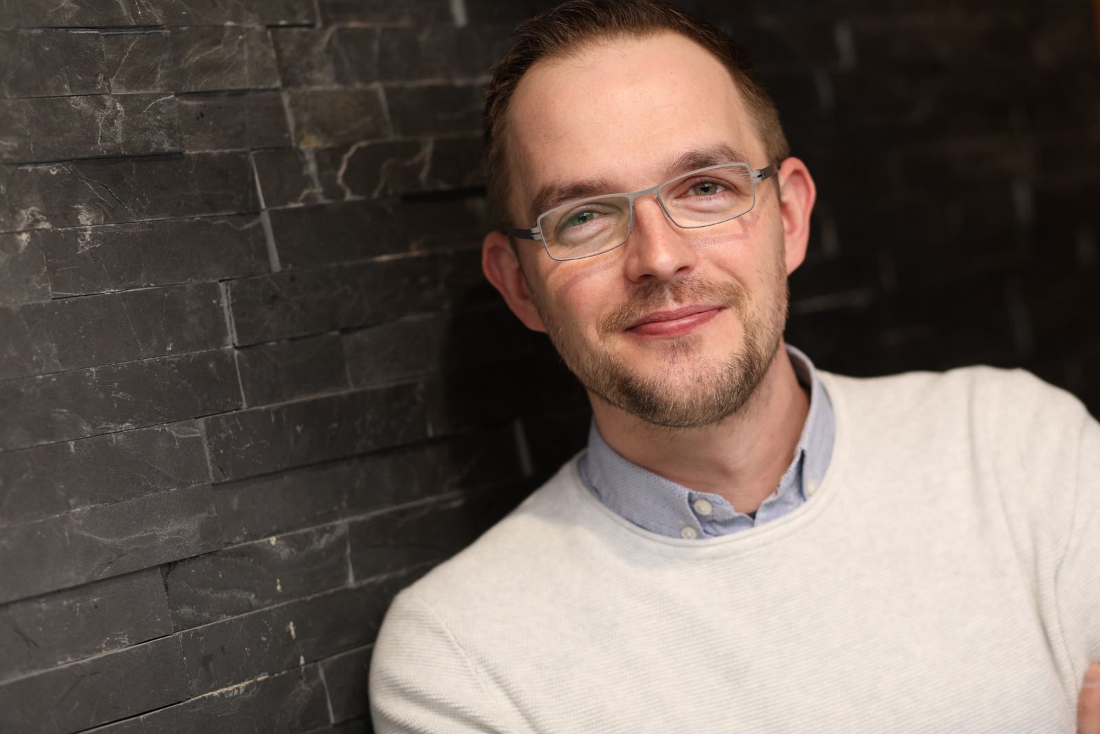Tobias Kammer, lächelnd, an eine Schieferwand gelehnt